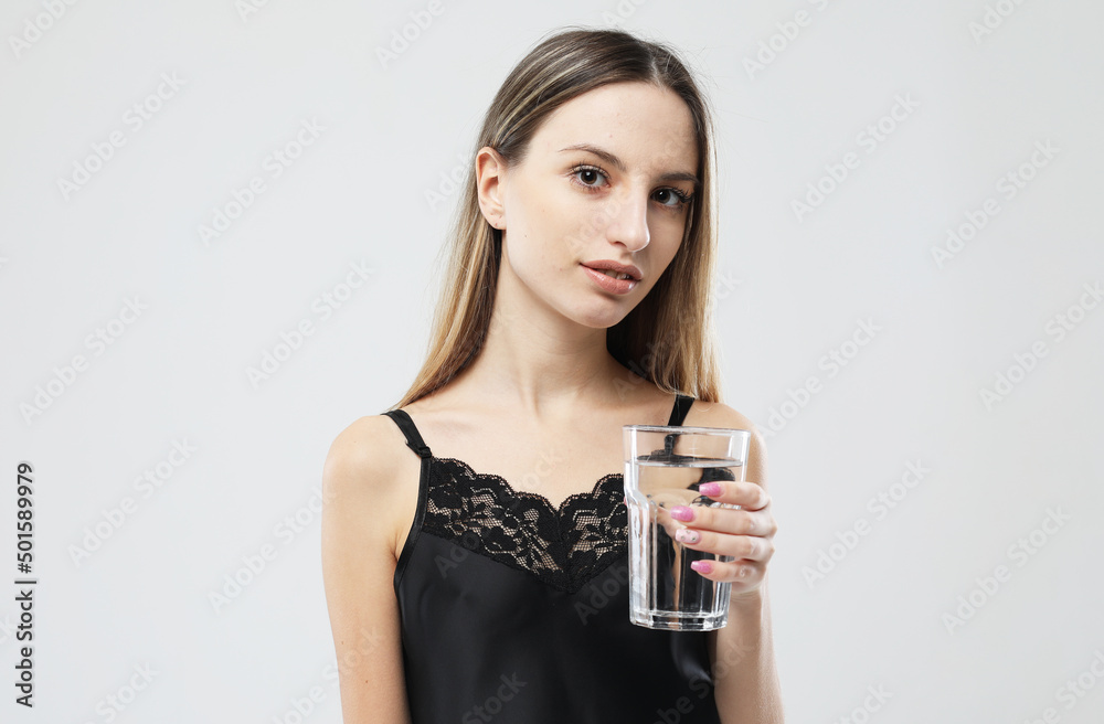 young woman wearing pajamas holding a glass of water young woman wearing pajamas holding a glass of water