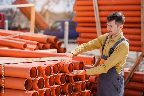 man builder contractor is choosing a sewage pipe from pipes store and preparing for sewer installation..