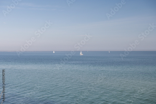 Blue sky without clouds with clear water and sailboards away from the coast in north Germany