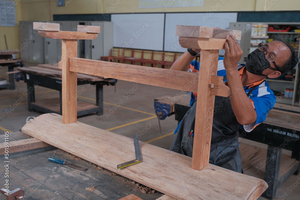 Senior male woodworker making console table in workshop. Joinery work on the production of wooden furniture. Small Business Concept Senior male woodworker making console table in workshop. Joinery work on the production of wooden furniture. Small Business Concept
