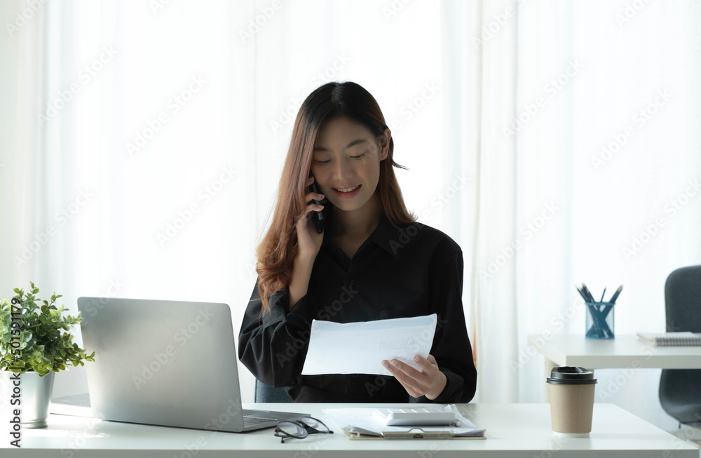 Beautiful young Asian businesswoman charming smiling and talking on the mobile phone in the office. Beautiful young Asian businesswoman charming smiling and talking on the mobile phone in the office.