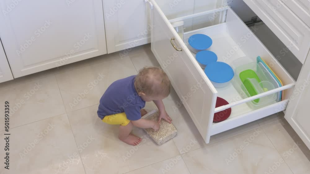 Baby boy having fun playing at home exploring the kitchen, curious toddler opening shelf of the kitchen cabinet taking out kitchen utensils. Infant learn exploring environment. High quality 4k footage Baby boy having fun playing at home exploring the kitchen, curious toddler opening shelf of the kitchen cabinet taking out kitchen utensils. Infant learn exploring environment. High quality 4k footage