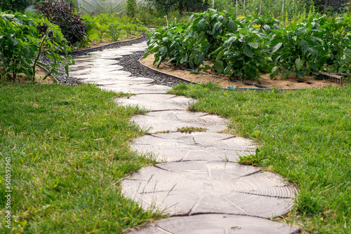 Path of plated stones on gravel bed. Garden architecture  pathway accessory to garden pond.