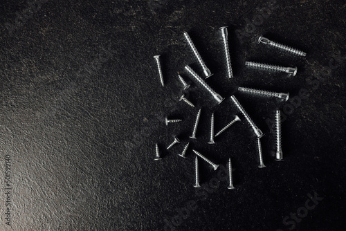 Self-tapping screws on floor. On a wooden background. High quality photo