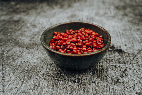 Pink peppercorns in a bowl on a stone table