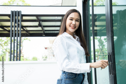 Asian business woman use key for lock or unlock glass door at house projects. Concept of real estate agent or receiving house for rent