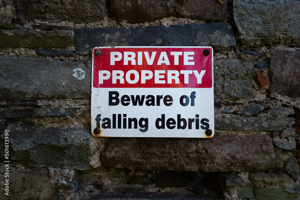 private property, beware of falling debris sign on wall of old ruins private property, beware of falling debris sign on wall of old ruins
