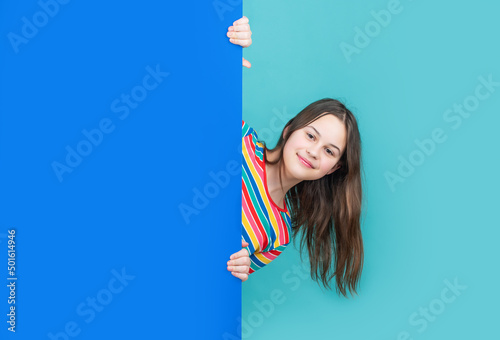 Картината върху платно glad kid behind blank blue paper with copy space for advertisement