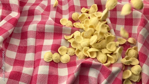 Orecchiette pasta fall on red checkered tablecloth, Italian pasta from Puglia made with durum wheat flour and water photo