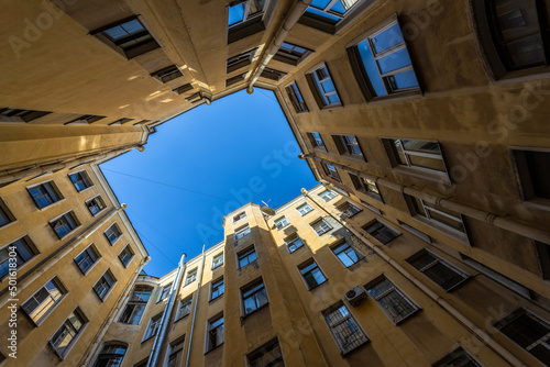 "Yard-well" of yellow residential buildings closed in a circle with a blue sky in st. petersburg 