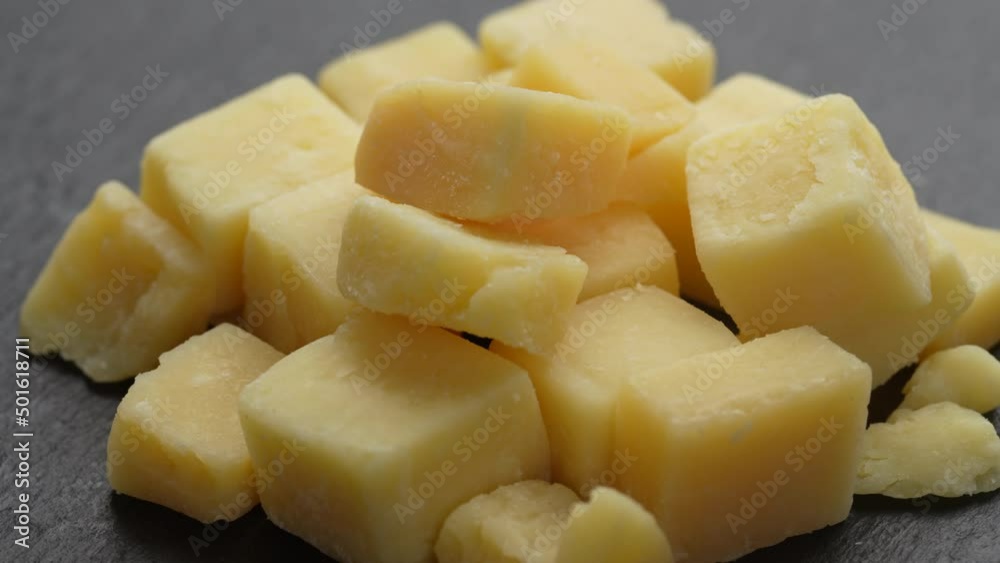 Diced cheese rotates on a black plate. Delicious cheese cubes, close up. Dairy products concept Diced cheese rotates on a black plate. Delicious cheese cubes, close up. Dairy products concept