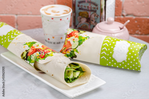 Eco packaging - roll (burrito) with vegetables in cardboard packaging for the delivery service. Vegan food.