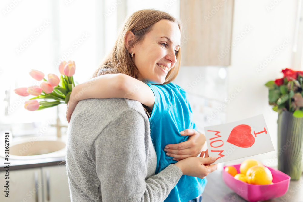 Happy Mother's Day! Happy little boy congratulating his mom and giving her flowers tulips and greeting card with red heart drawn Happy Mother's Day! Happy little boy congratulating his mom and giving her flowers tulips and greeting card with red heart drawn