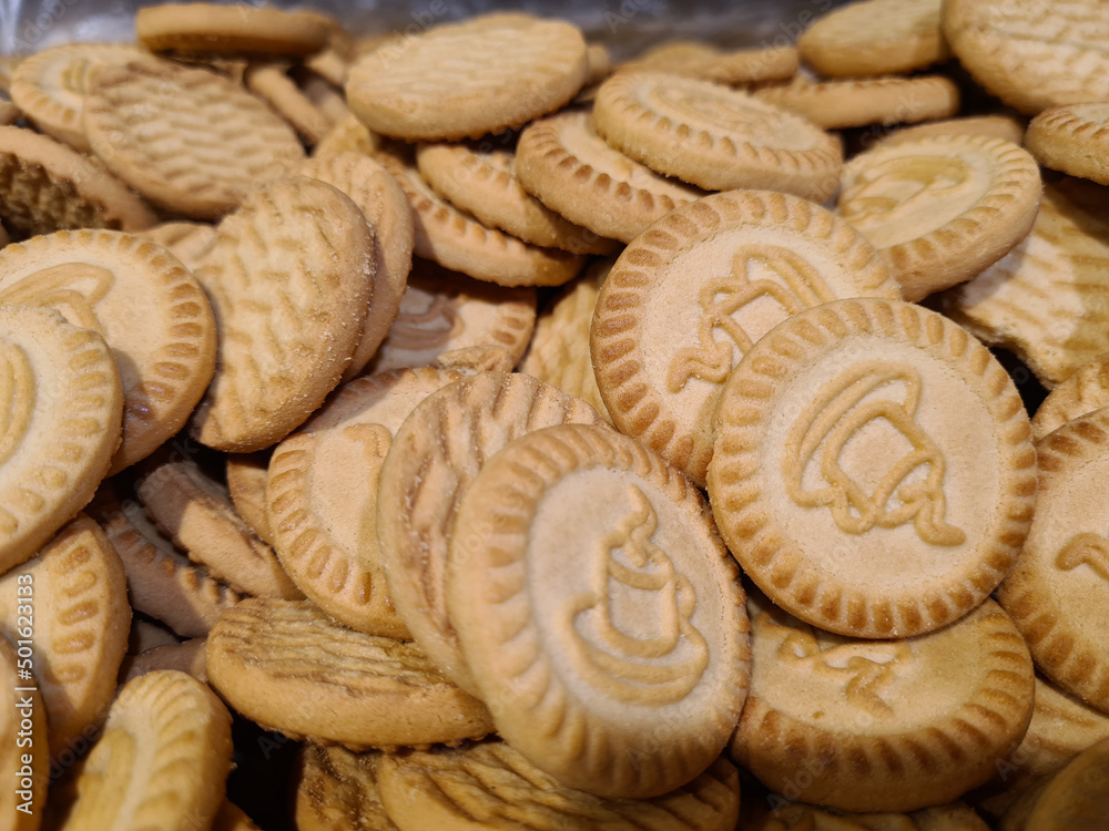 Closeup of large number of round cookies with patterned cup of tea