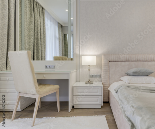 Close-up bright bedroom with bed, large mirror and dressing table © Artbovich