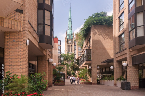 Toronto, Canada - 08 03 2018: Summer view along the passage between the buildings of Front Street East on the tower of The Cathedral Church of St. James, an 1853 Gothic Revival cathedral photo