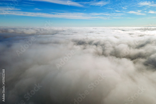 Aerial view from above of white puffy clouds in bright sunny day
