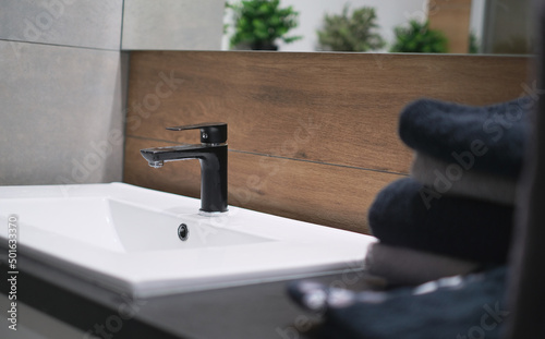 Fotografija Close-up, bathroom interior, washbasin with mirror, black faucet and dark towels