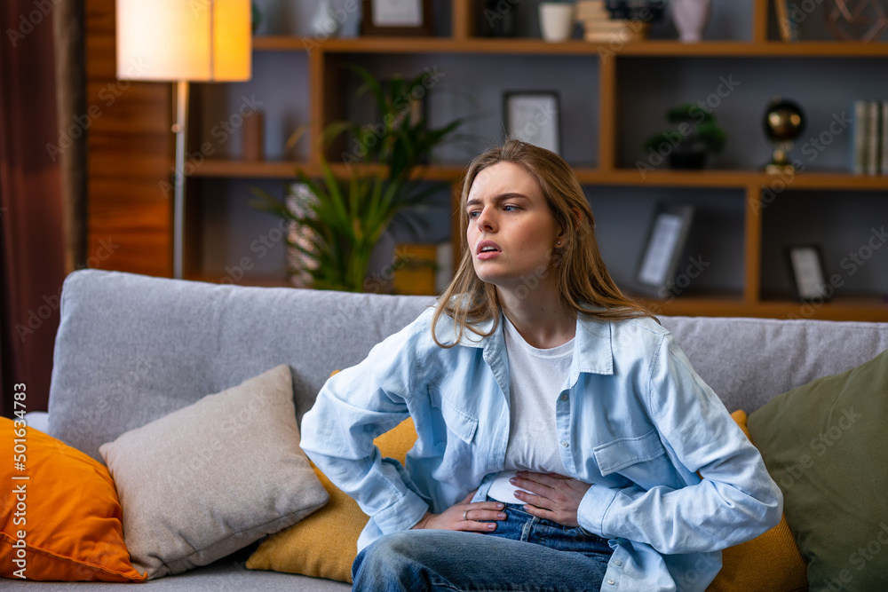 Unhappy beautiful woman suffering from stomach ache at home. PMS, Inflammation and infection. Food poisoning Unhappy beautiful woman suffering from stomach ache at home. PMS, Inflammation and infection. Food poisoning