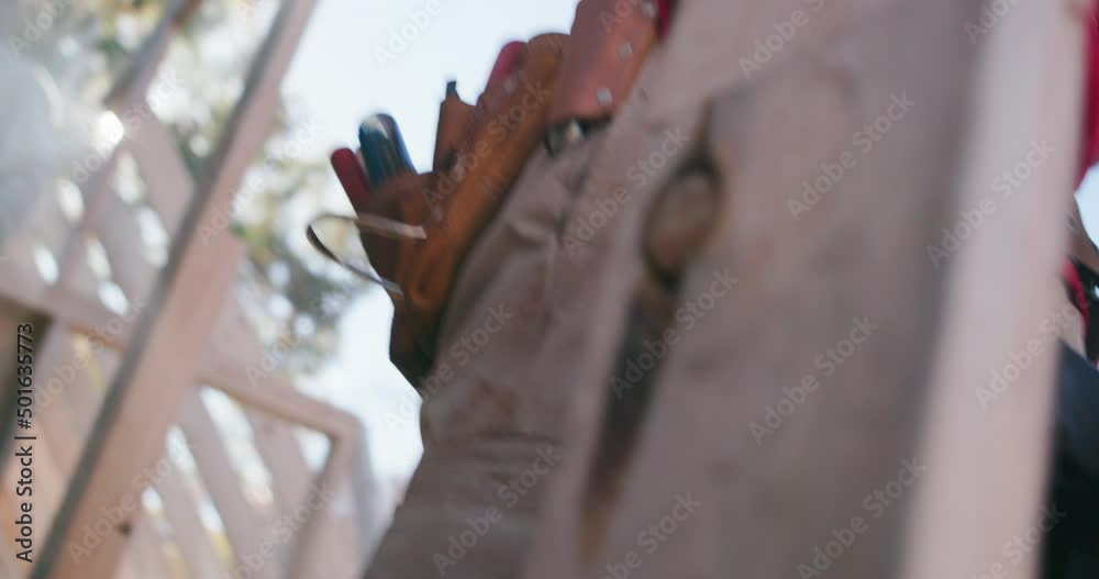 Construction worker grabs a hammer from his tool belt while building a house Construction worker grabs a hammer from his tool belt while building a house