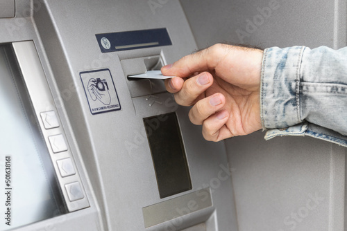 Male hand inserting ATM card into ATM bank machine