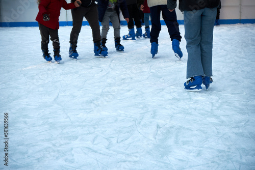 Group of feet in blue skates on an ice rink. Hobbies and sports. Vacations and winter activities.