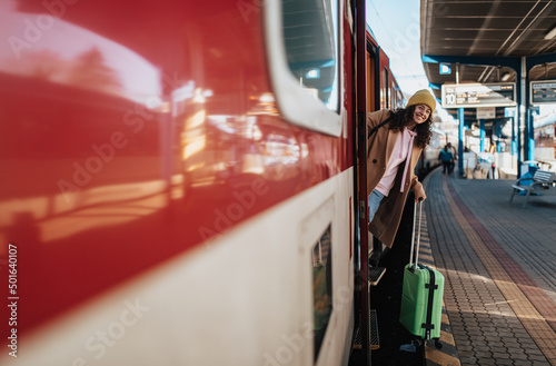 Photos Happy young traveler woman with luggage getting off the train at train station p
