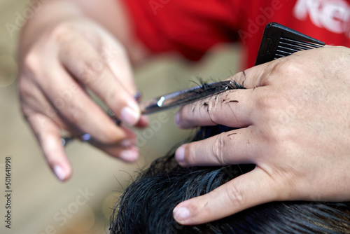 Barber cutting the hair of a male using scissors