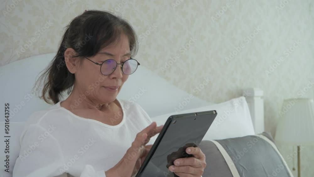 Holiday concept of 4k Resolution. Asian old woman using a tablet in the bedroom. Holiday concept of 4k Resolution. Asian old woman using a tablet in the bedroom.