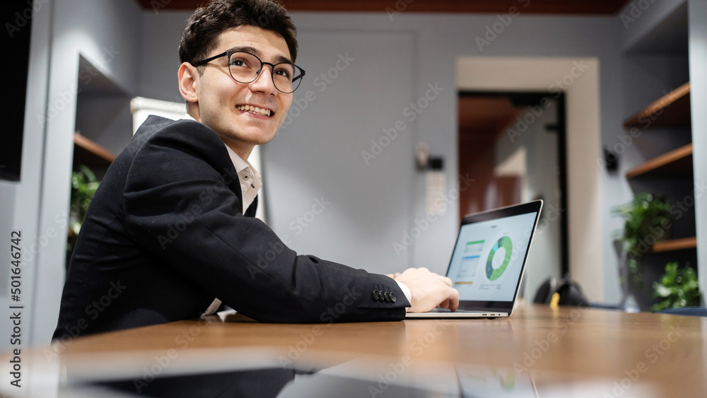 The manager is a man in glasses business suit working in the office, writes a message to the partner by e-mail The manager is a man in glasses business suit working in the office, writes a message to the partner by e-mail