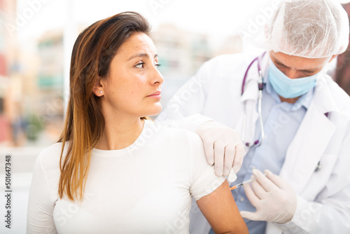 Doctor male giving Covid-19 or flu antivirus vaccine shot to female patient at health clinic or hospital office