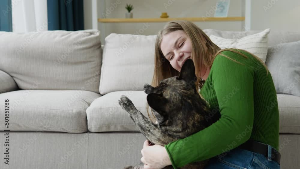 Happy young girl is fooling around and playing with a dog in sunny living room. Happy domestic animal concept, best friends Happy young girl is fooling around and playing with a dog in sunny living room. Happy domestic animal concept, best friends