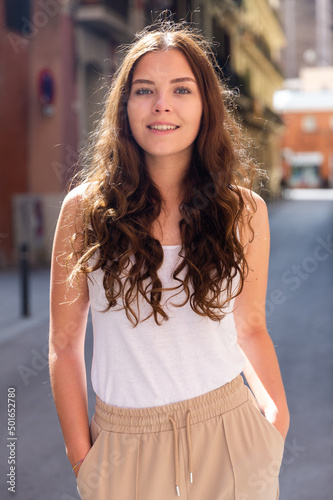 Portrait of a positive confident girl, standing in good weather on the street