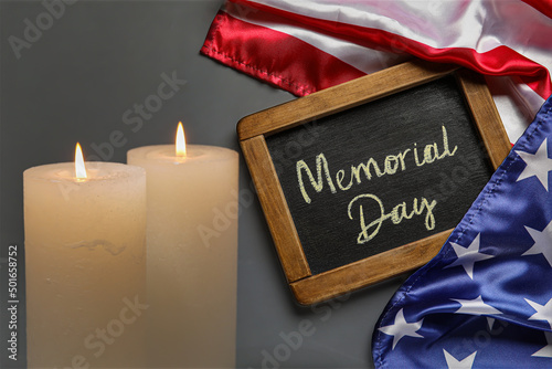 Chalkboard with text MEMORIAL DAY, USA flag and burning candles on dark background