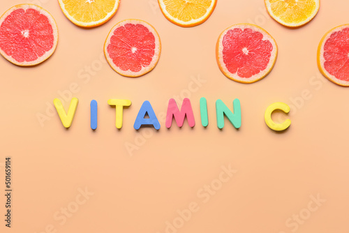 Text VITAMIN C made of colorful letters and citrus fruits on color background