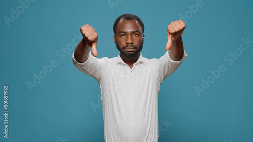 Foto Displeased upset man showing thumbs down gesture, advertising rejection and disapproval about opinion