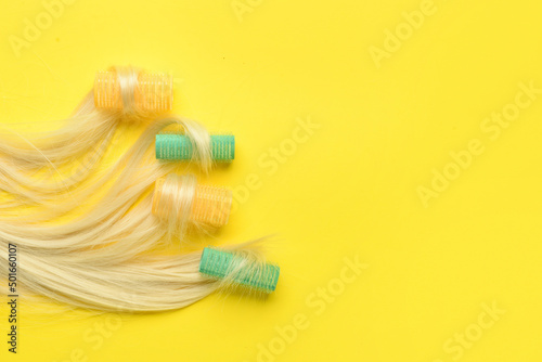 Blonde hair strands with curlers on yellow background