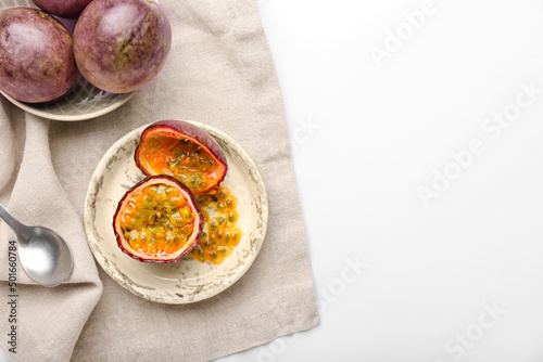 Plate with delicious passion fruits on white background