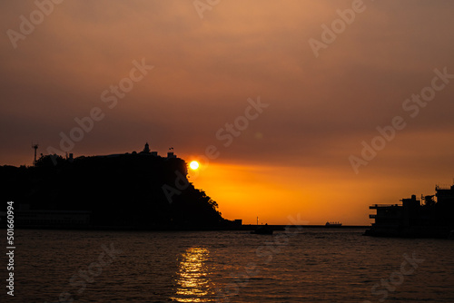 Sunset and sunlight at Kaohsiung harbor, a landscape of mountain with lighthouse and coastline silhouette colorful background in kaohsiung city, Taiwan.