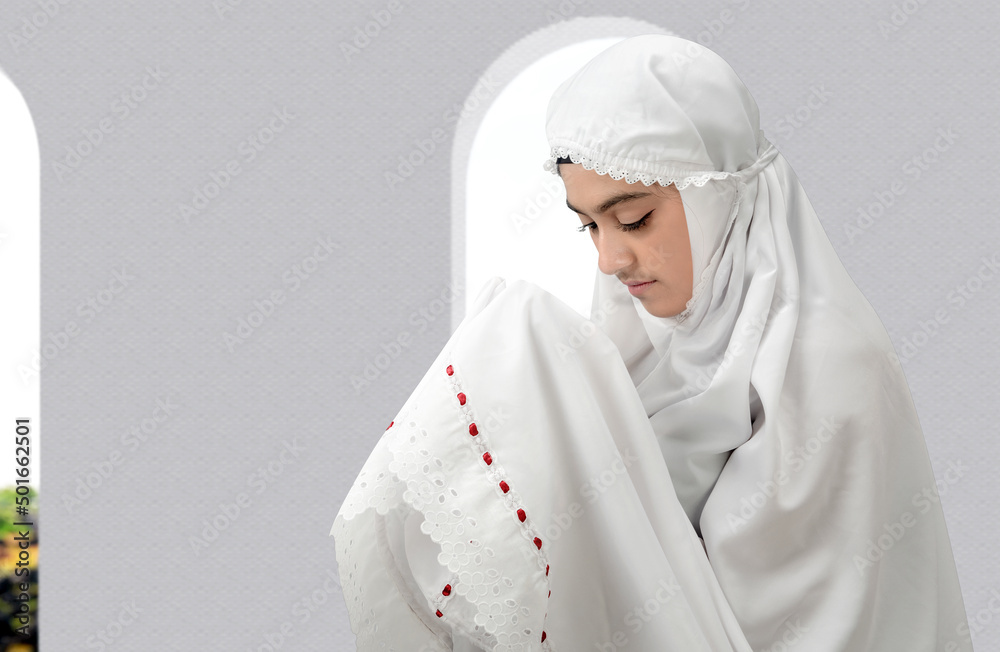 Asian Muslim woman in a veil standing while raised hands and praying