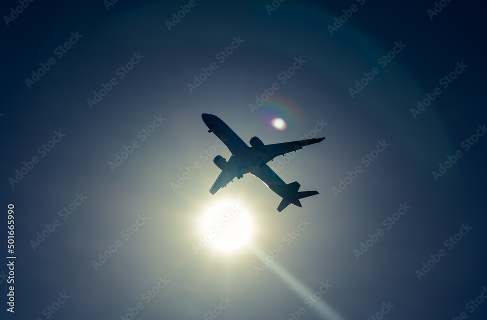dark airplane silhouette on the sun, blue sky background with reflections. dark airplane silhouette on the sun, blue sky background with reflections.