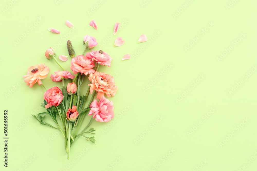 Top view image of pink flowers composition over green wooden background