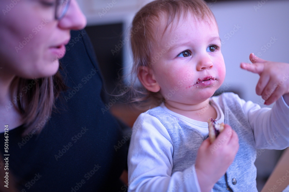 Mother holding her cute little boy who is eating cookie Mother holding her cute little boy who is eating cookie