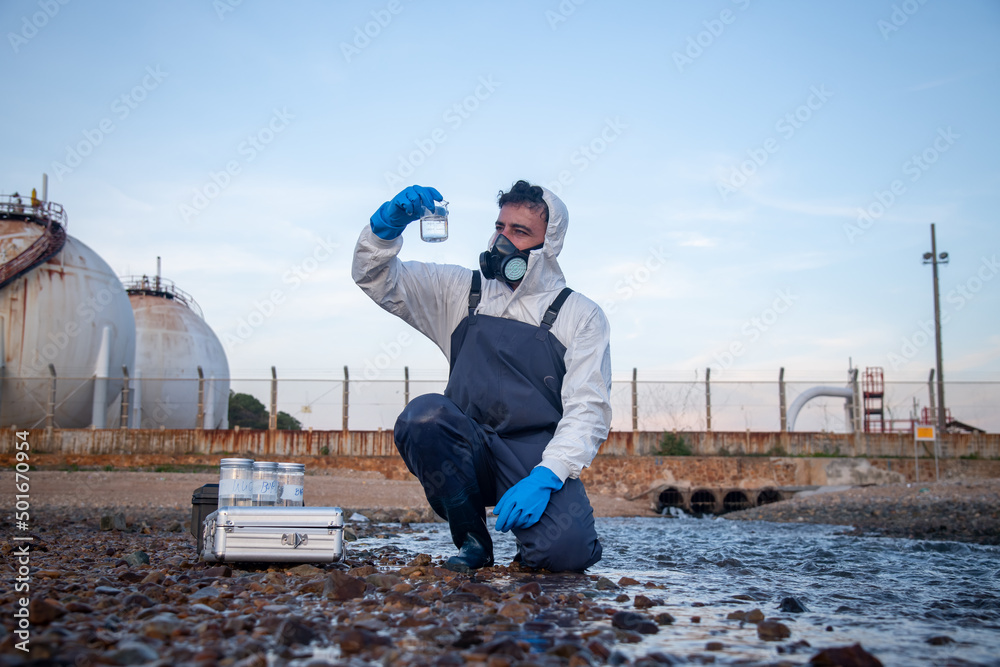 Scientist wearing protective  uniform and glove under working water analysis and water quality by get waste water to check case in laboratory is environment pollution problem concept