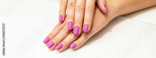 Beautiful manicure with purple, pink nail polish on young caucasian female hands