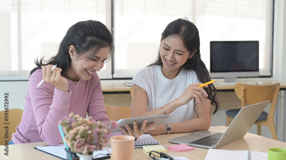 Friendly female colleagues discussing new project together at creative office. Friendly female colleagues discussing new project together at creative office.