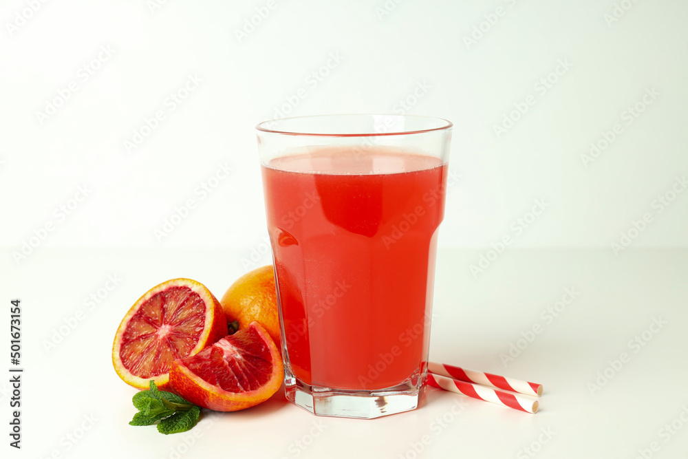 Concept of fresh drink with red orange juice on white table Concept of fresh drink with red orange juice on white table
