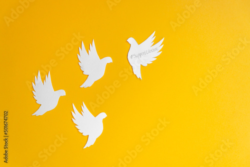 Four white paper dove birds as a symbol of peace isolated on yellow background. Peace to Ukraine. World Peace Day.