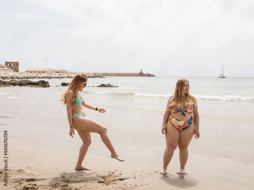Fototapeta premium two women playing on the beach, one curvy and one skinny body