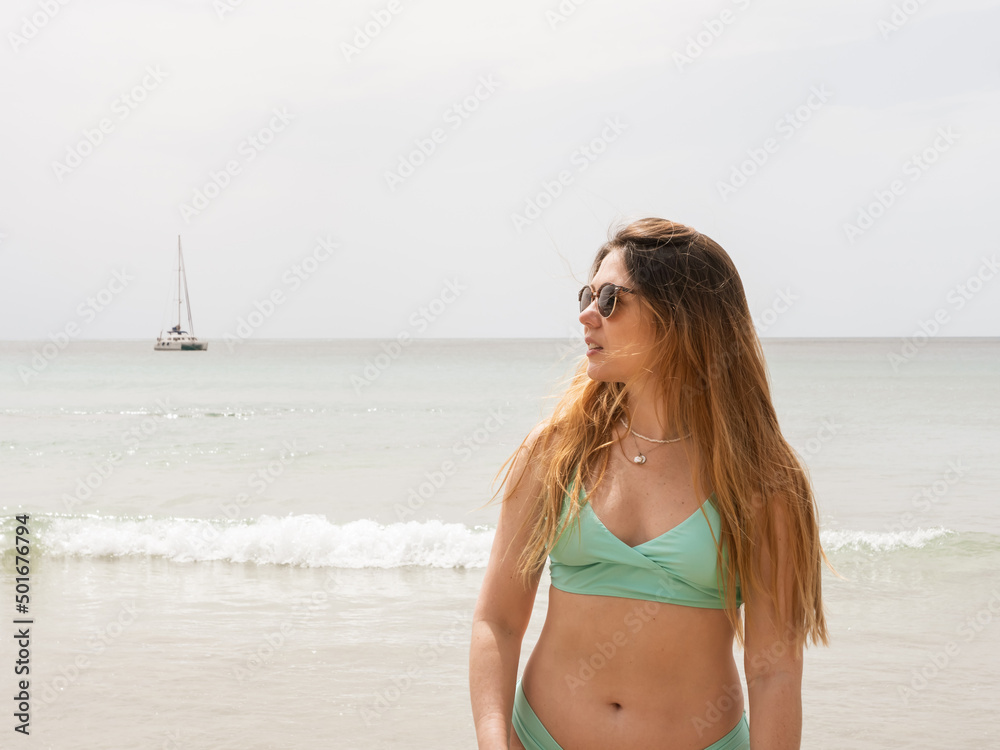 beautiful woman seeing the beach with sailboat on the background beautiful woman seeing the beach with sailboat on the background